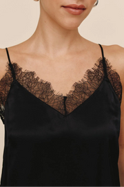 Woman wearing a black lace-trimmed top against a beige background