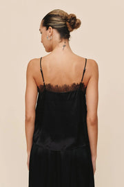 Woman wearing a black satin slip dress with lace trim on a beige background