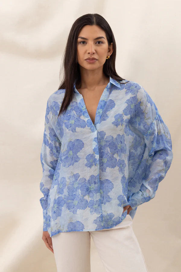 Woman wearing a blue floral long-sleeve button-up blouse with a relaxed fit, front