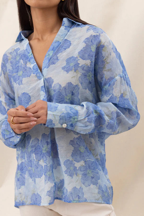 Woman wearing a blue floral long-sleeve button-up blouse with a relaxed fit, detail