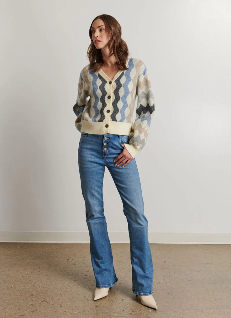Woman wearing a patterned sweater and blue jeans against a plain background