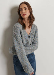 Woman wearing a gray knitted cardigan against a plain background