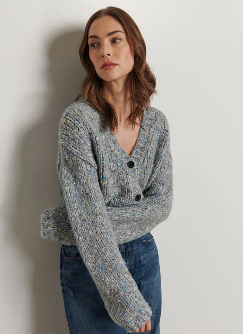 Woman wearing a gray knitted cardigan against a plain background