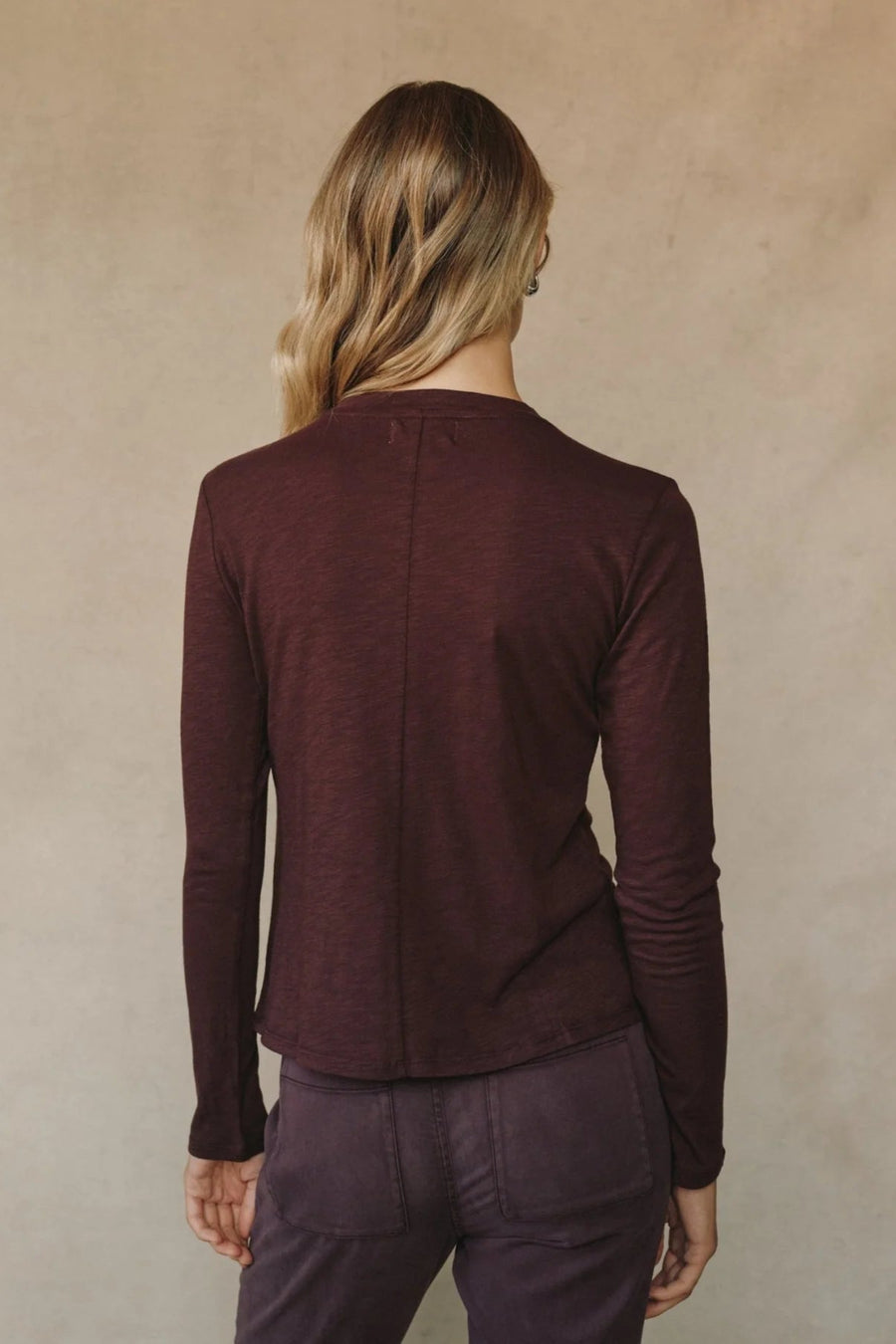 Back view of woman wearing a burgundy long sleeve crew neck tee
