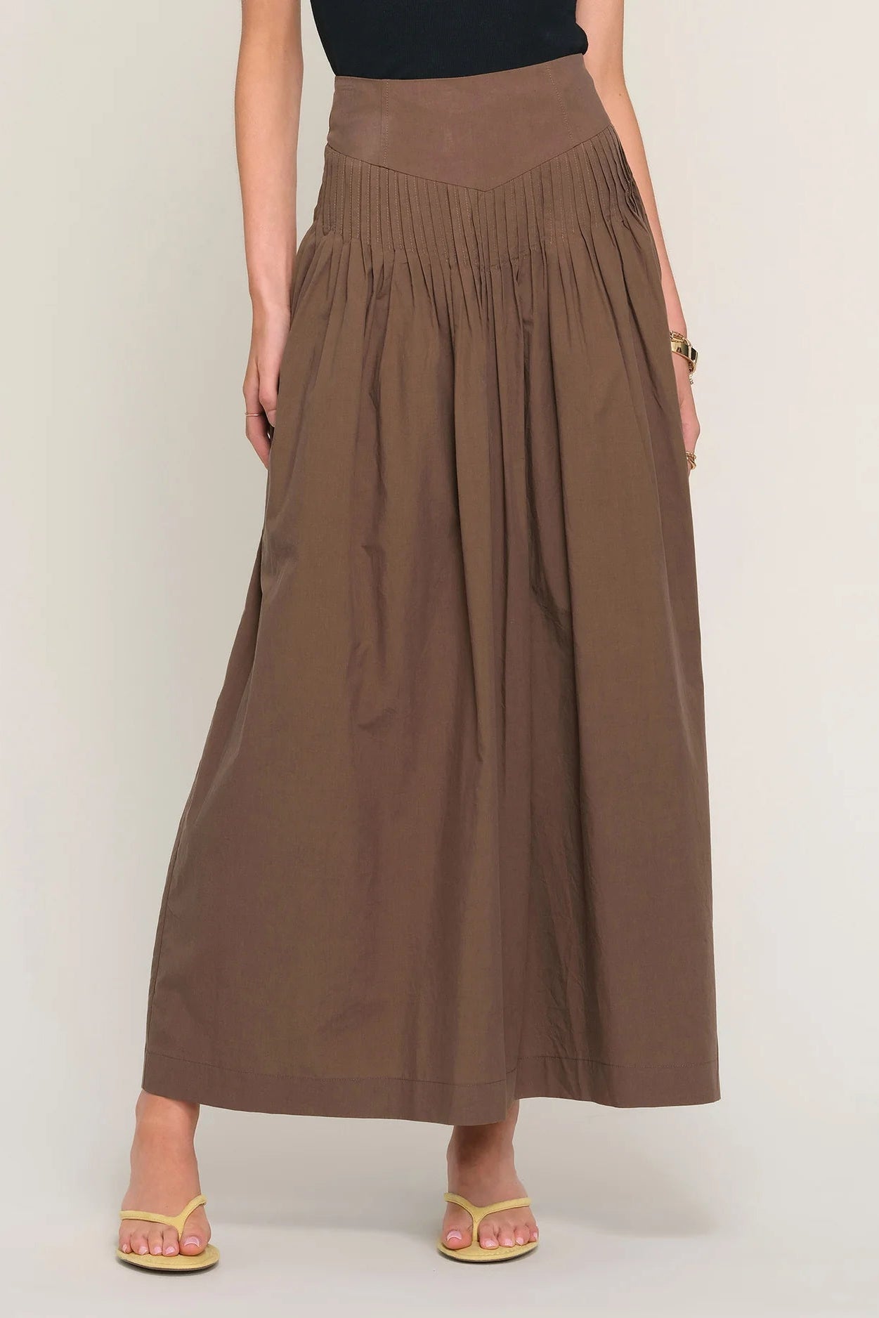 woman wearing a brown high-waisted pleated maxi skirt, front