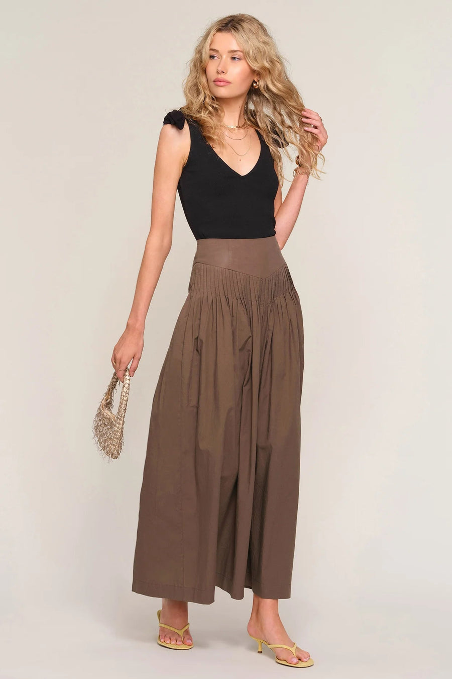 woman wearing a brown high-waisted pleated maxi skirt, front