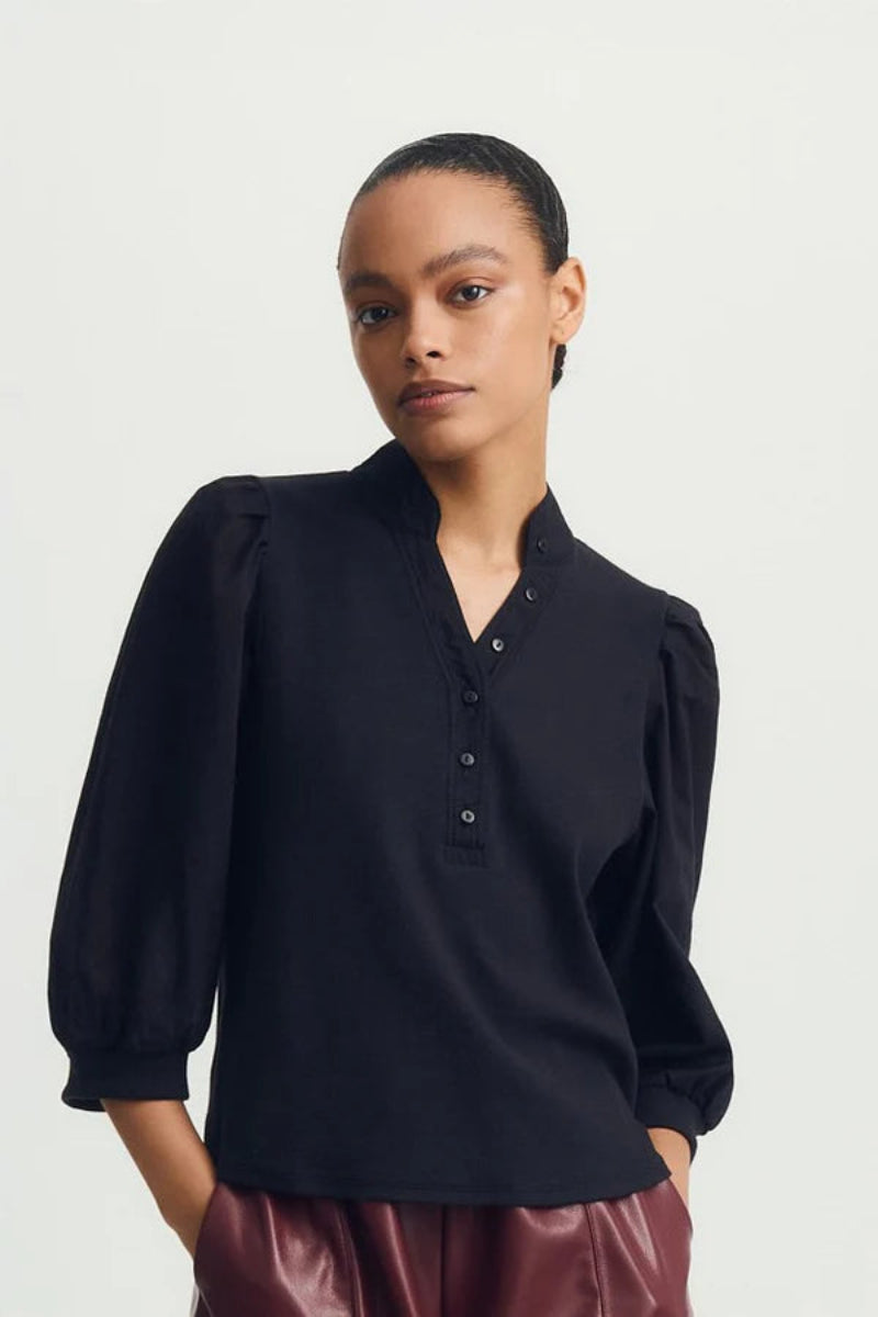 Woman wearing a black blouse with puffed sleeves on a white background