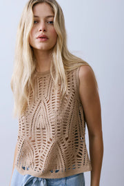 Woman wearing a beige sleeveless crochet knit top with an openwork pattern, front