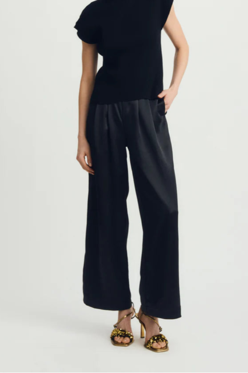 Woman wearing a black sleeveless top and wide-leg pants on a white background