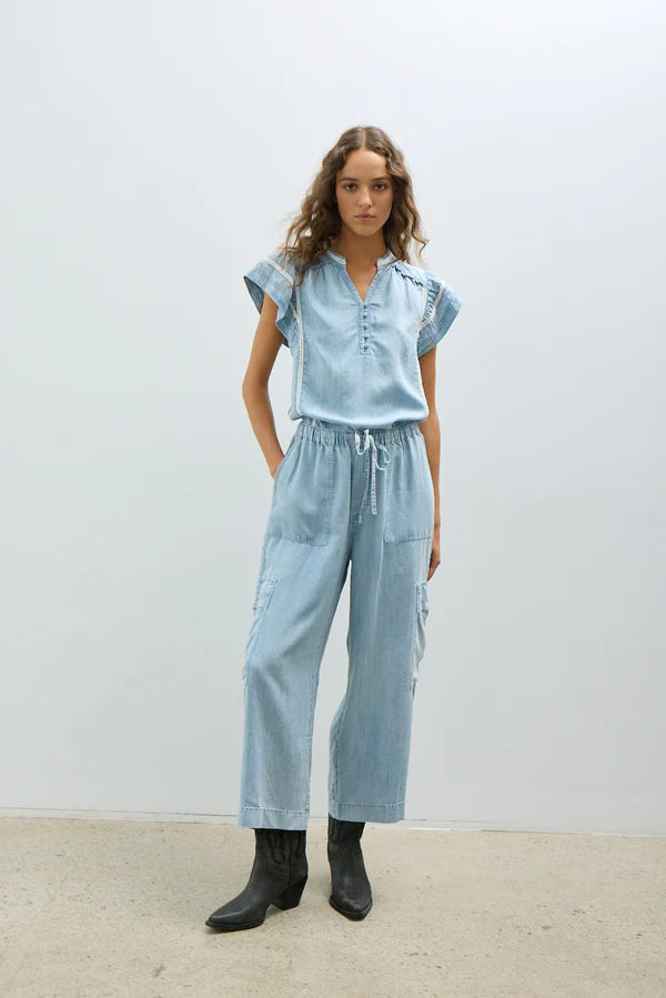 Light wash chambray wide-leg pants with a drawstring waist, utility-style cargo pockets, and a relaxed cropped fit.
