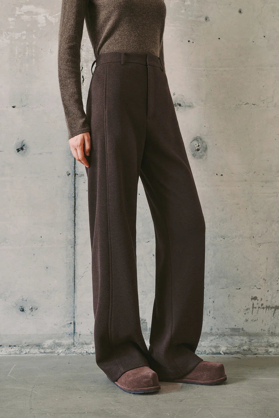 Woman wearing dark brown high-waisted wide-leg trousers, side
