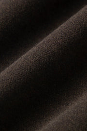 Woman wearing dark brown high-waisted wide-leg trousers, fabric detail