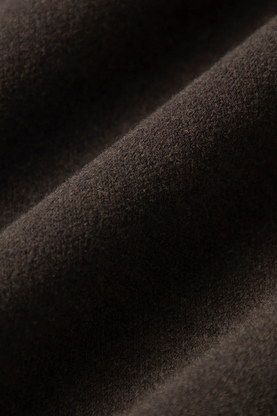 Woman wearing dark brown high-waisted wide-leg trousers, fabric detail