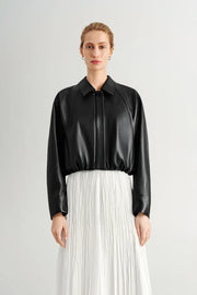 Woman wearing a black long-sleeve collared faux leather jacket, front