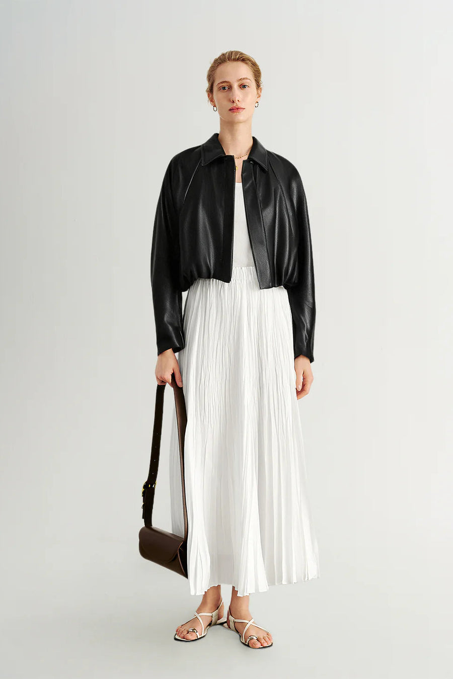 Woman wearing a black long-sleeve collared faux leather jacket, front