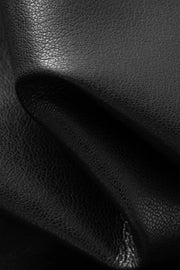 Woman wearing a black long-sleeve collared faux leather jacket, fabric detail