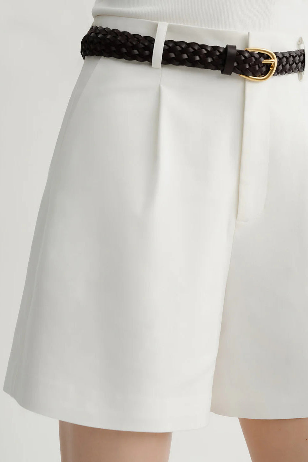 Woman wearing white tailored high-waisted shorts, detail view