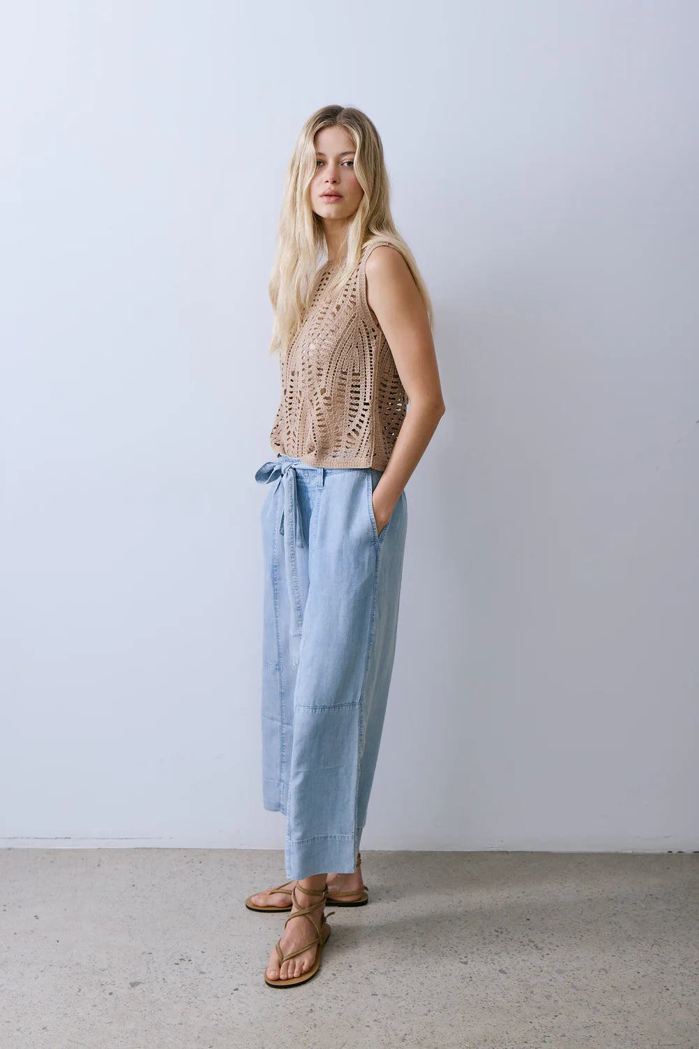 Woman wearing light blue chambray wide-leg pants with a drawstring waist, side view