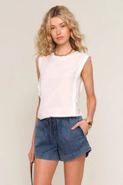 woman wearing a white sleeveless top with a relaxed fit paired with blue drawstring shorts, front