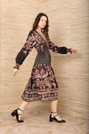 Side view of woman wearing a black, pink and brown patterned long sleeve midi dress