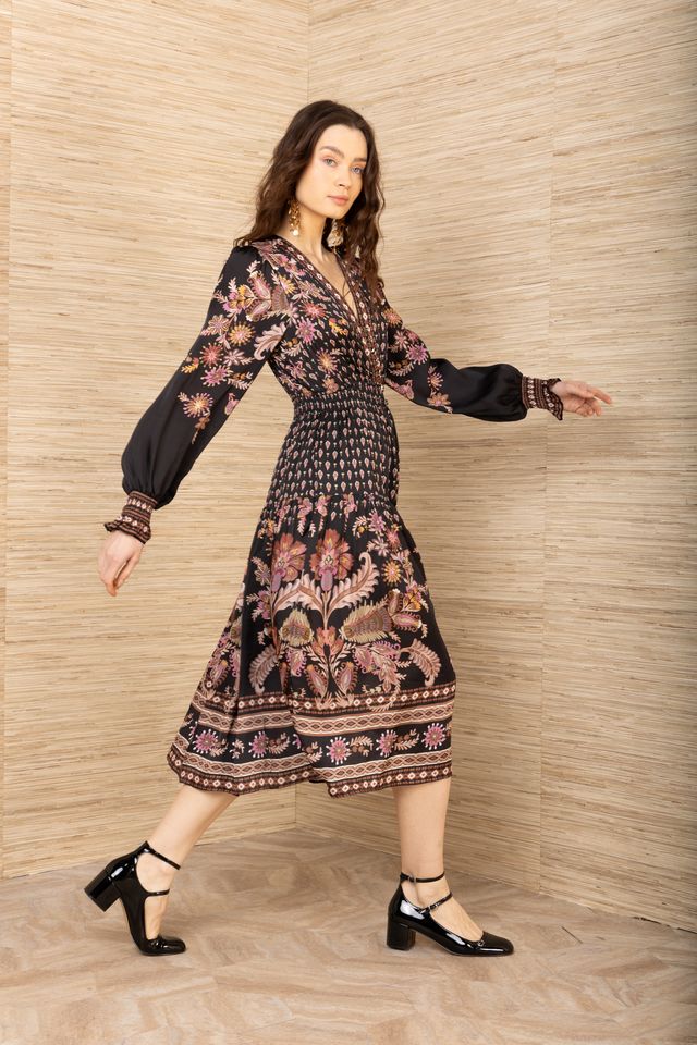 Side view of woman wearing a black, pink and brown patterned long sleeve midi dress