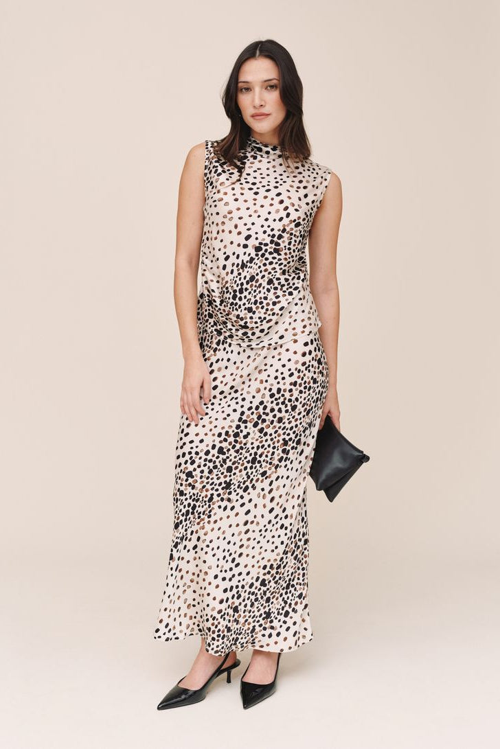 women wearing a white sleeveless cowl neck top with brown and black print 