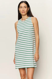 Woman wearing a sleeveless white shift dress with soft sage green horizontal stripes. The dress features a high crew neckline, an easy A-line silhouette, and falls above the knee, front