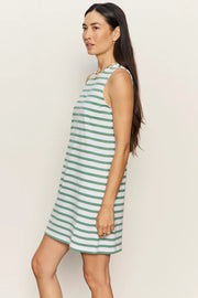 Woman wearing a sleeveless white shift dress with soft sage green horizontal stripes. The dress features a high crew neckline, an easy A-line silhouette, and falls above the knee, side