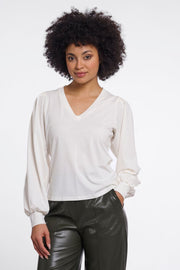 Woman wearing a white v-neck blouse. 
