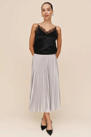 woman wearing a pleated silver skirt and a black lace top