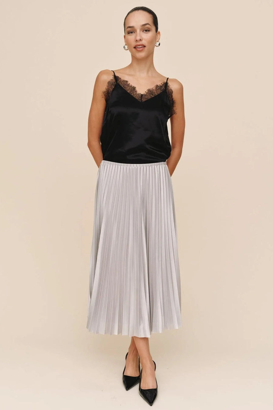 woman wearing a pleated silver skirt and a black lace top