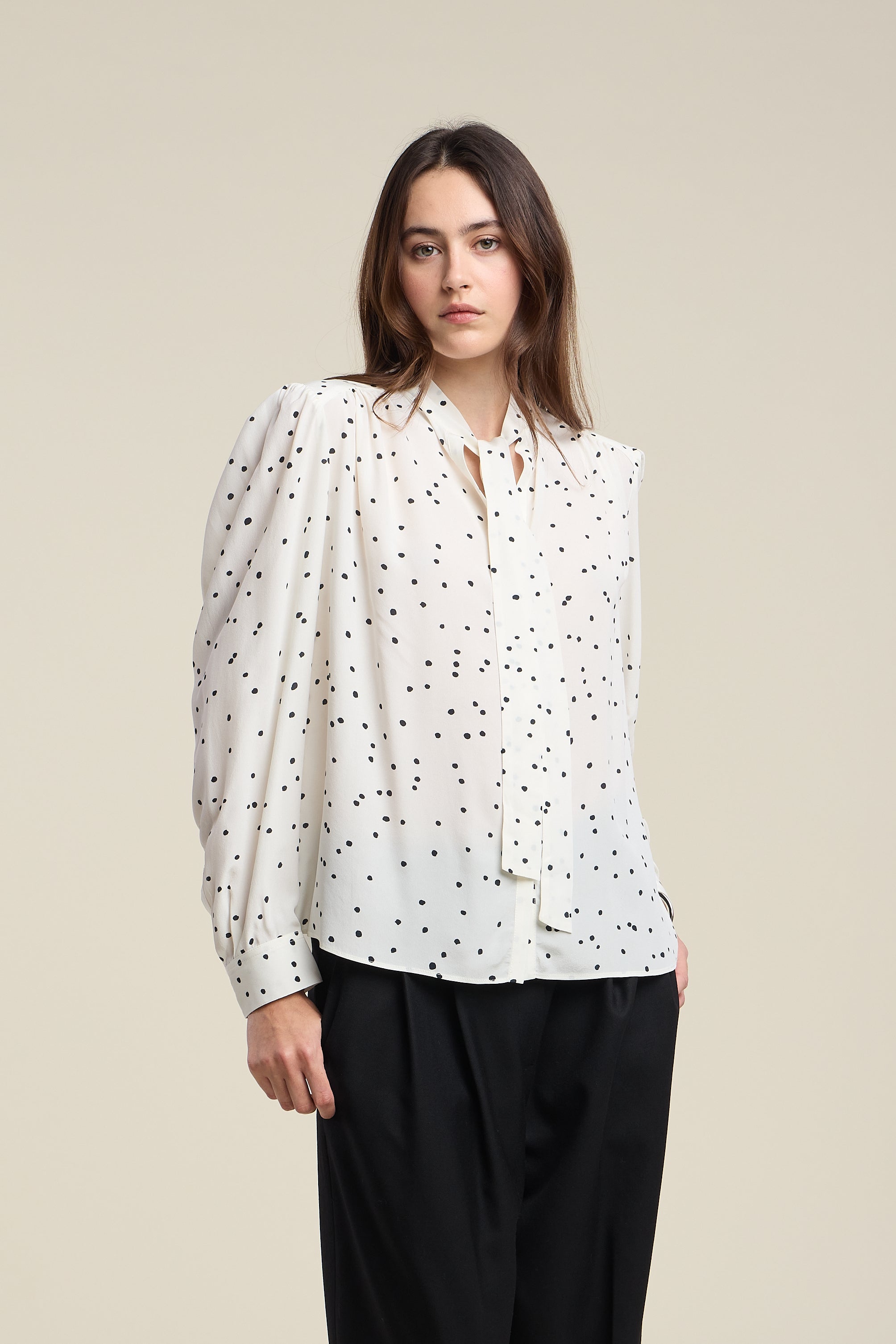 Woman wearing a white blouse with black polka dots 