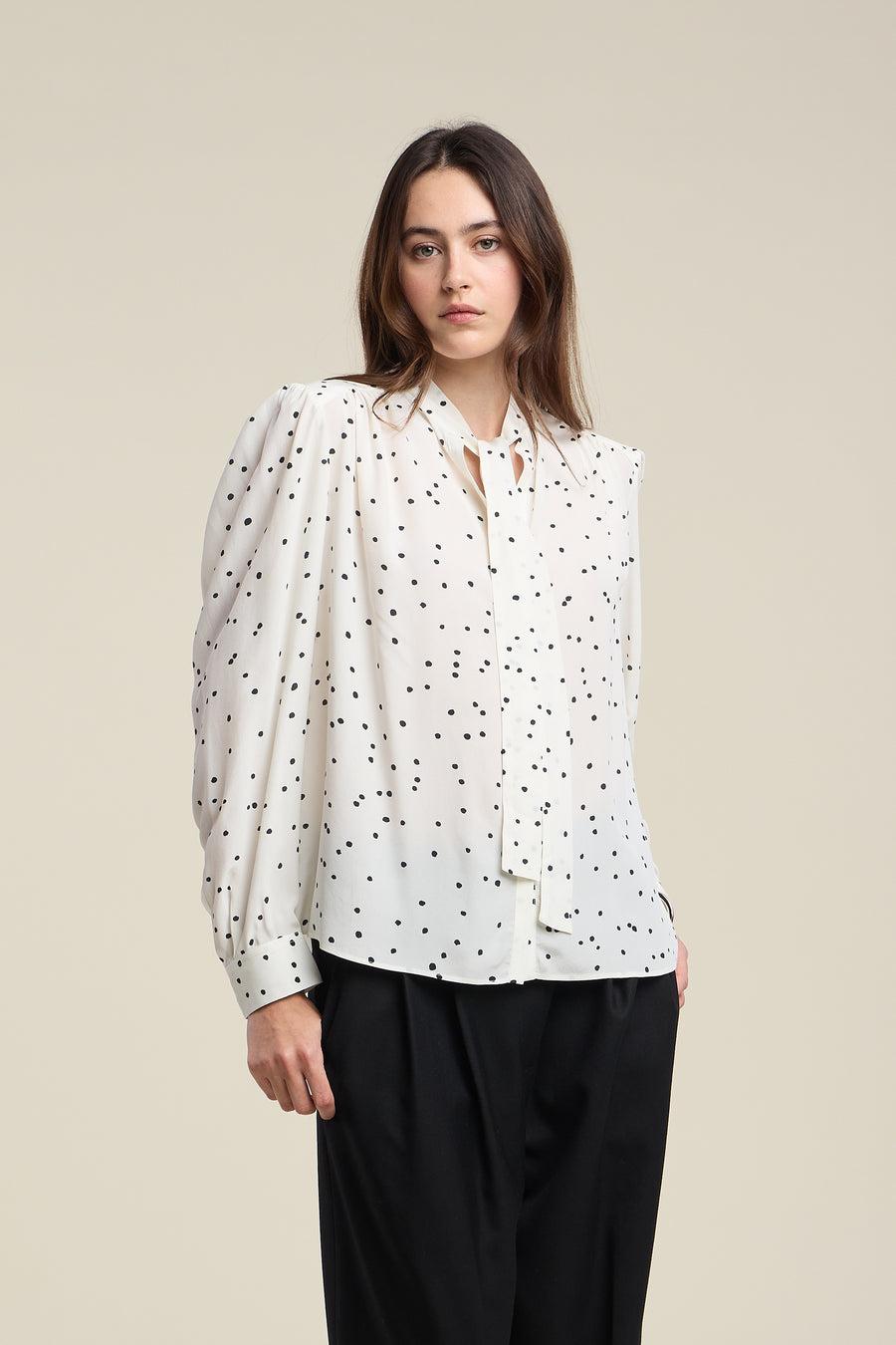 Woman wearing a white blouse with black polka dots 