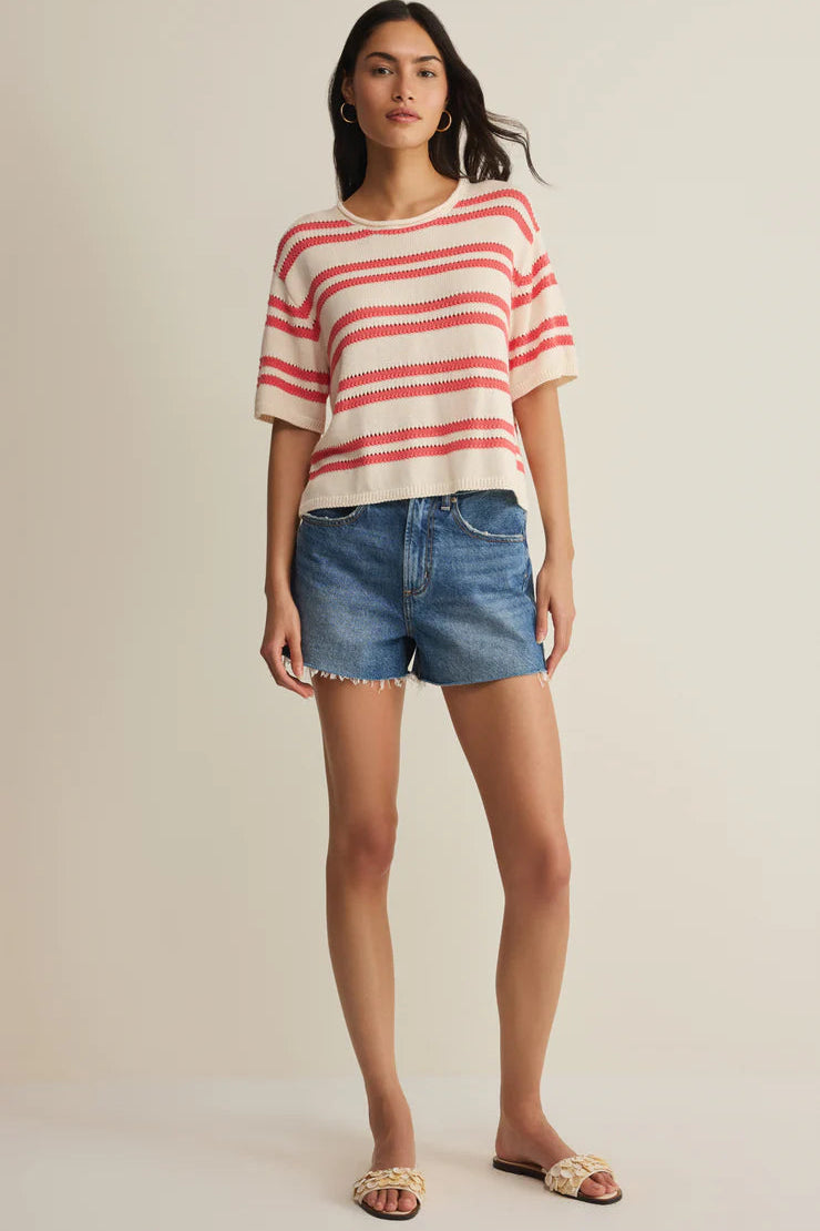 Woman wearing a cream short-sleeve knit top with red horizontal stripes, front