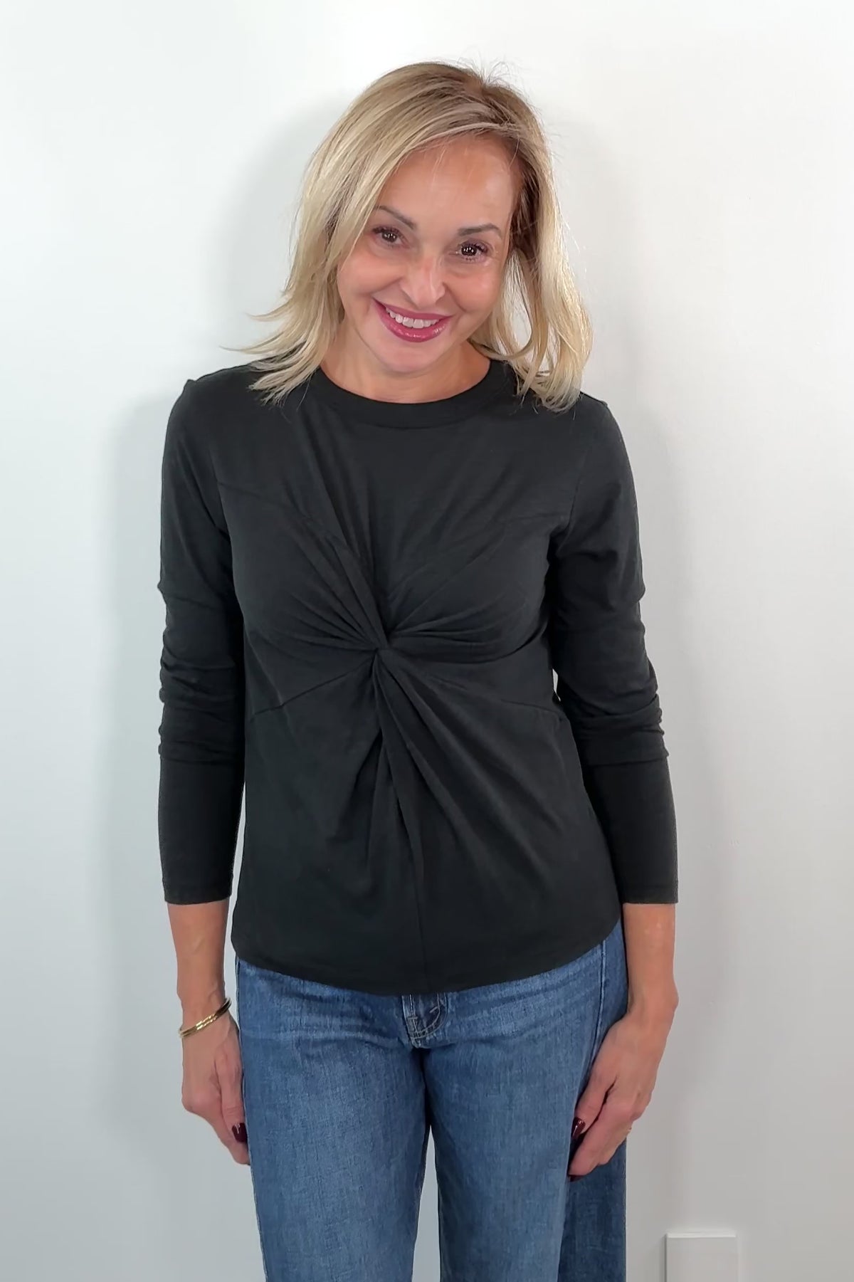 video of a woman wearing a black long-sleeve top with a knot detail 