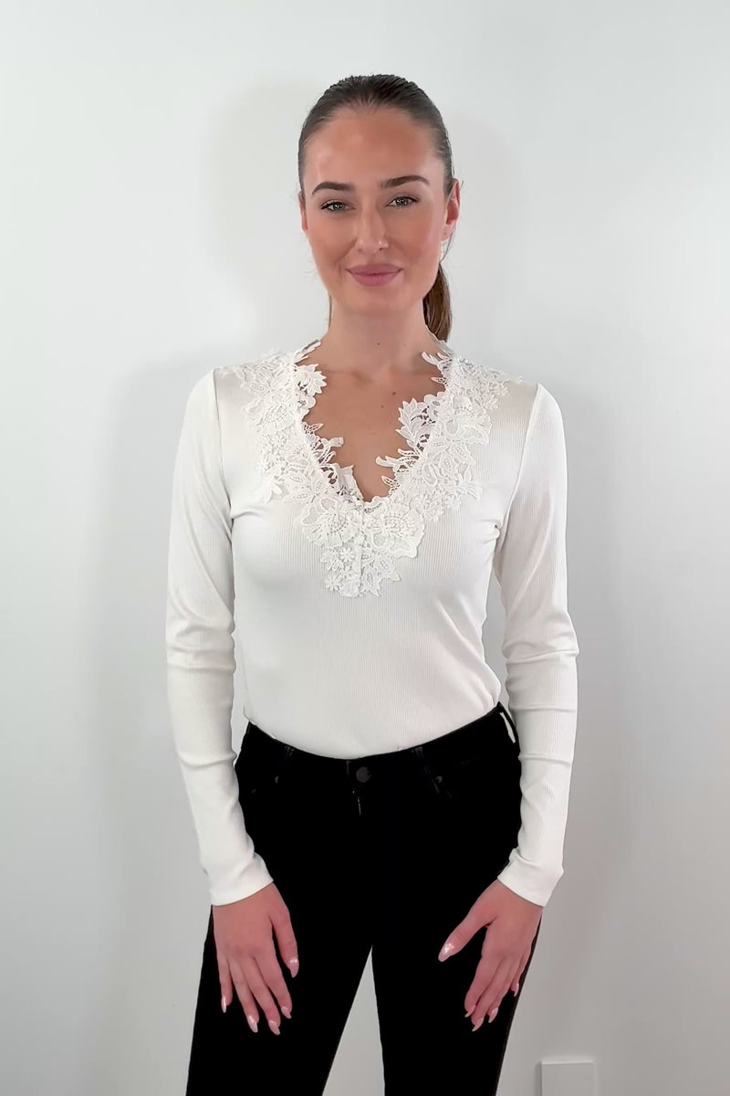 video of woman wearing a white ribbed top with lace details on the neckline