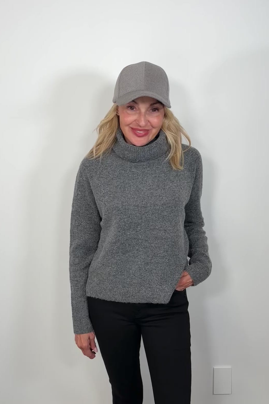 Video of a woman wearing a gray long sleeve turtle neck sweater