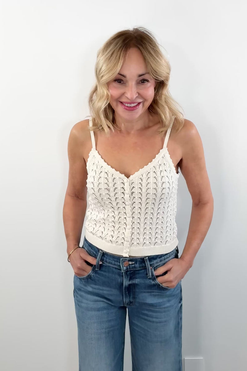 video of woman wearing a cream knit tanktop with buttons on the front and scallop knit pattern