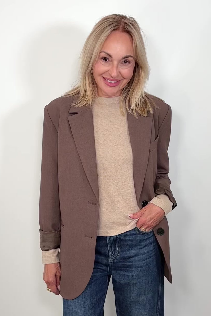 Video of woman wearing a cool brown blazer over a beige top open, turning around to show the back