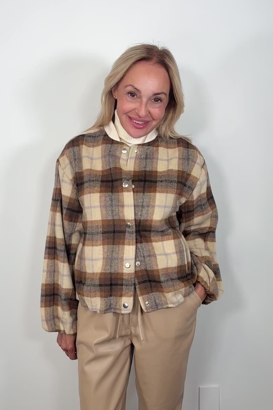 Video of a woman wearing a brown plaided bomber jacket