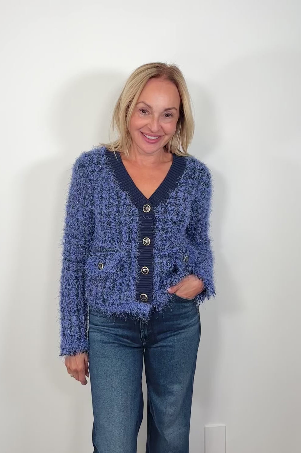 Video of woman wearing a fluffy blue cardigan with front pockets