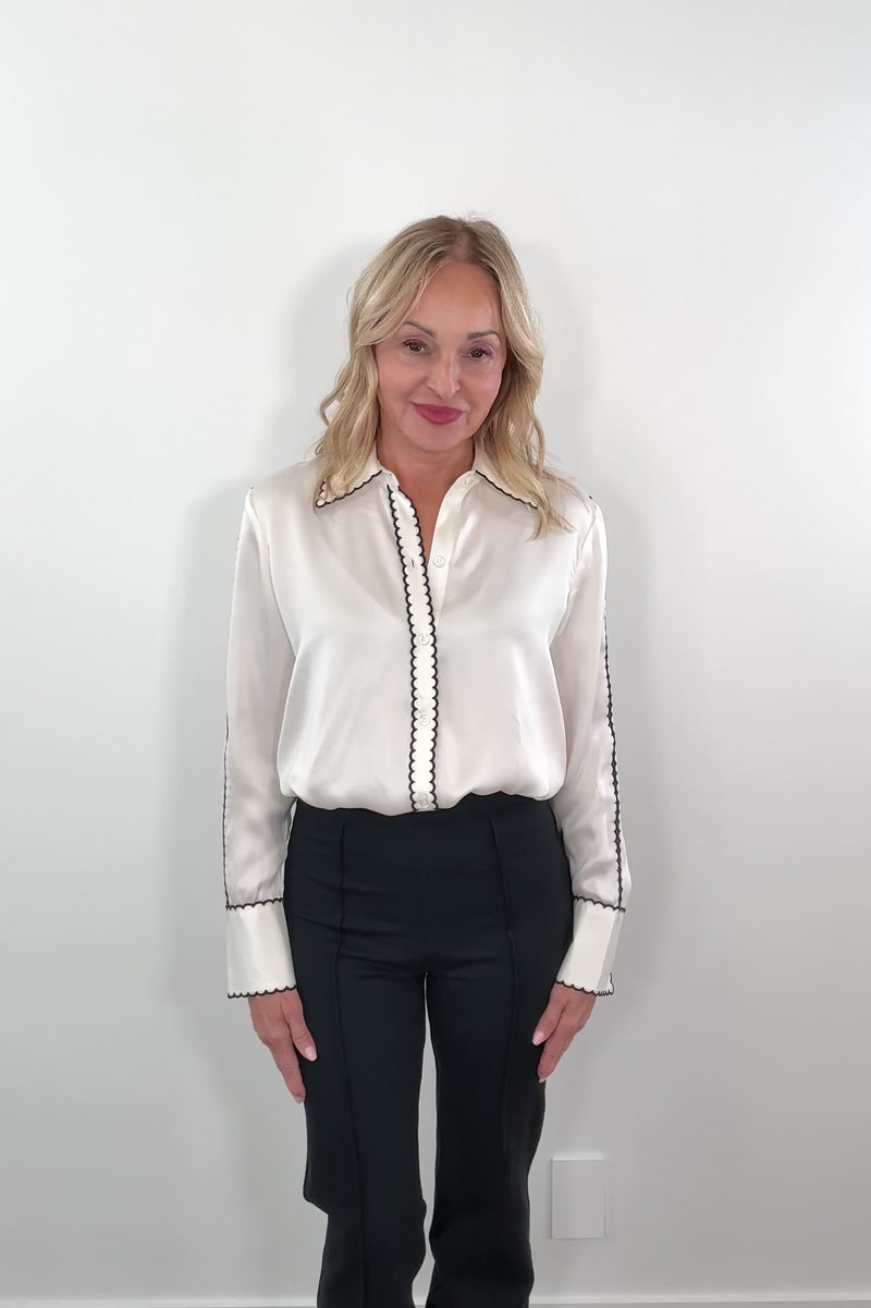 video of a woman wearing a silk cream blouse with black trimming