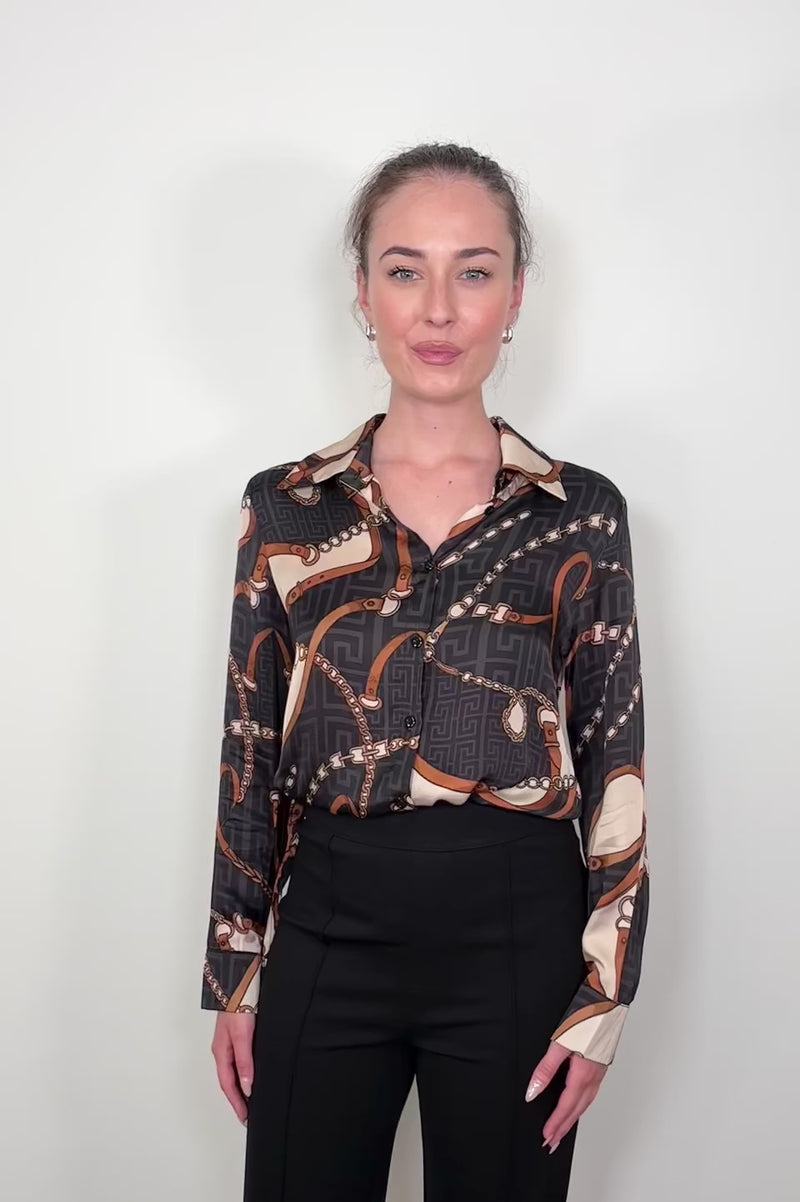 Video of woman wearing a printed button up shirt tucked in