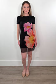 Video of a woman wearing a black dress with a mesh dress on top that has a floral design