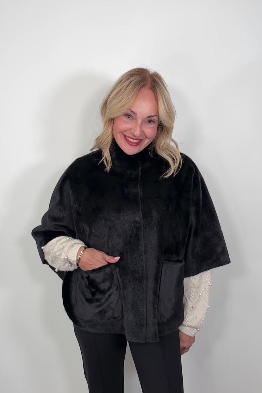 Video of a woman wearing a black short cape