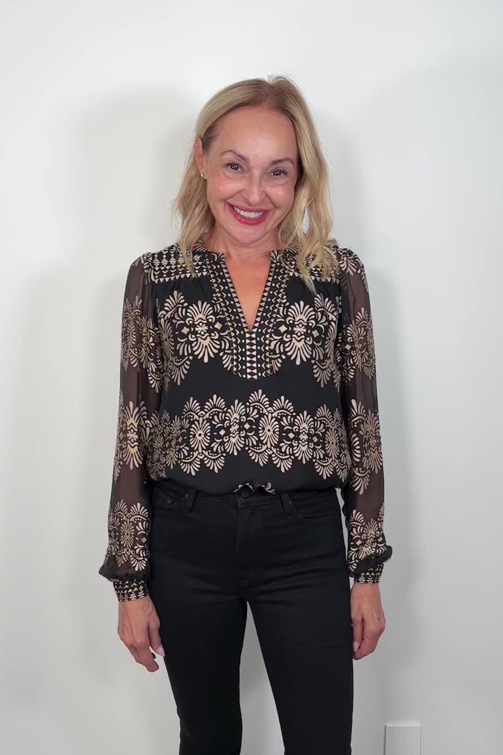 Video of woman wearing a silk mix black and gold long sleeve burnout blouse tucked in