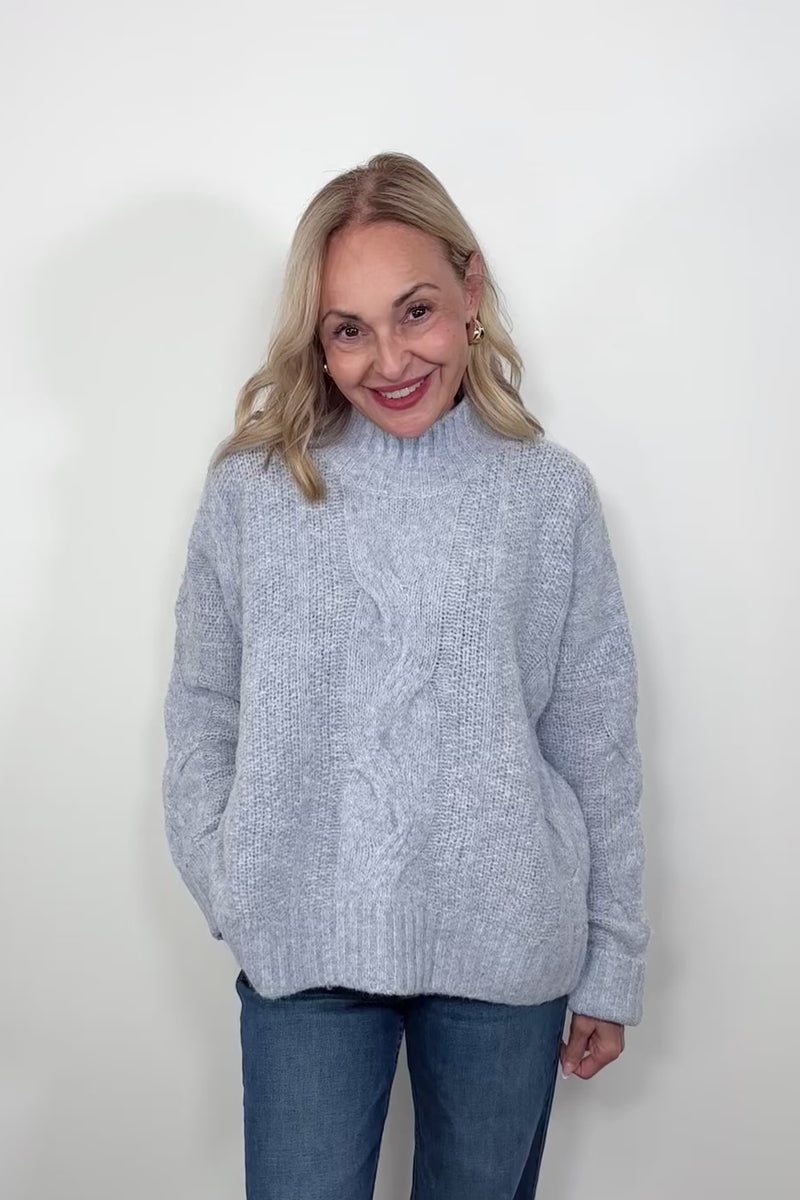 Video of woman wearing a high neck light blue knitted sweater 