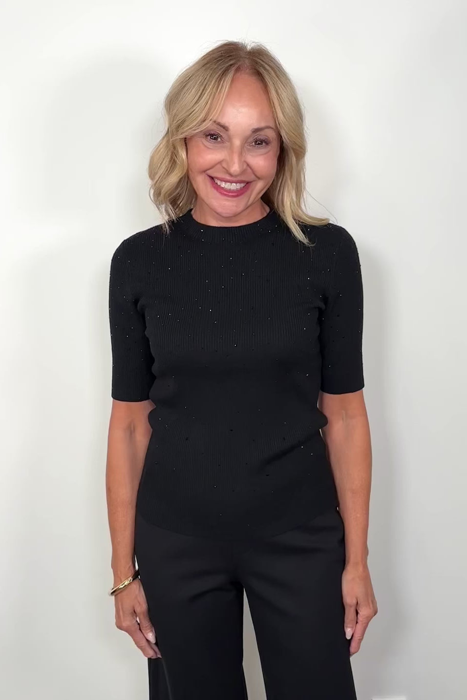 Video  of woman wearing a black ribbed tee with crystal embellishments 