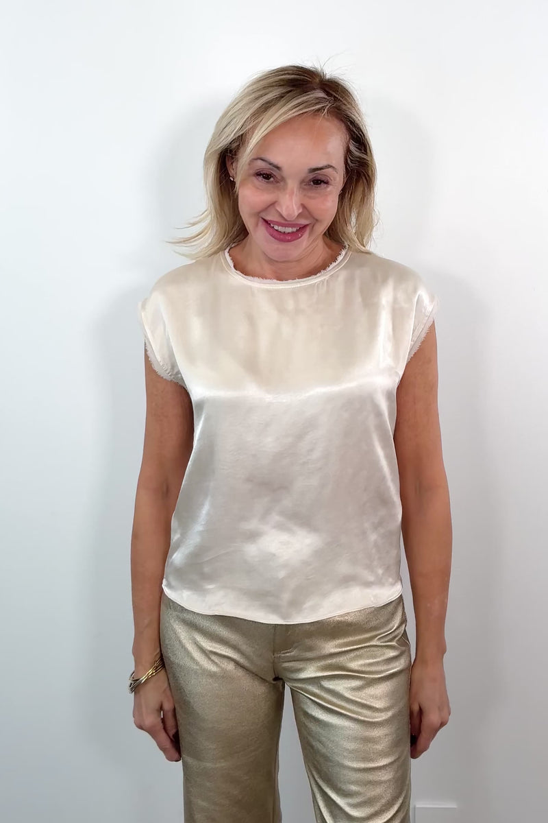 video of a woman wearing a cream satin cap sleeved top