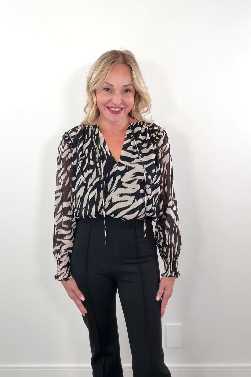 video of a woman wearing a lined animal pint chiffon blouse